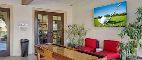 A pool table in a room with a ceiling fan, a no-smoking sign, and a framed picture of a golf ball on a tee.