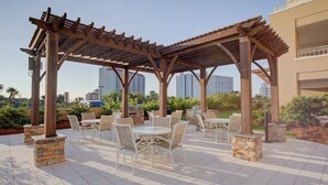 An outdoor patio with a pergola, stone pillars, and white outdoor furniture.