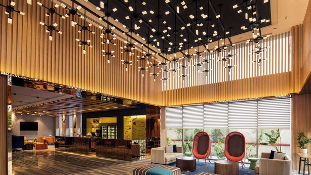 A spacious lobby with a high ceiling, modern lighting, and comfortable seating areas. - Ramada Encore by Wyndham Indore Nipania (Indore)