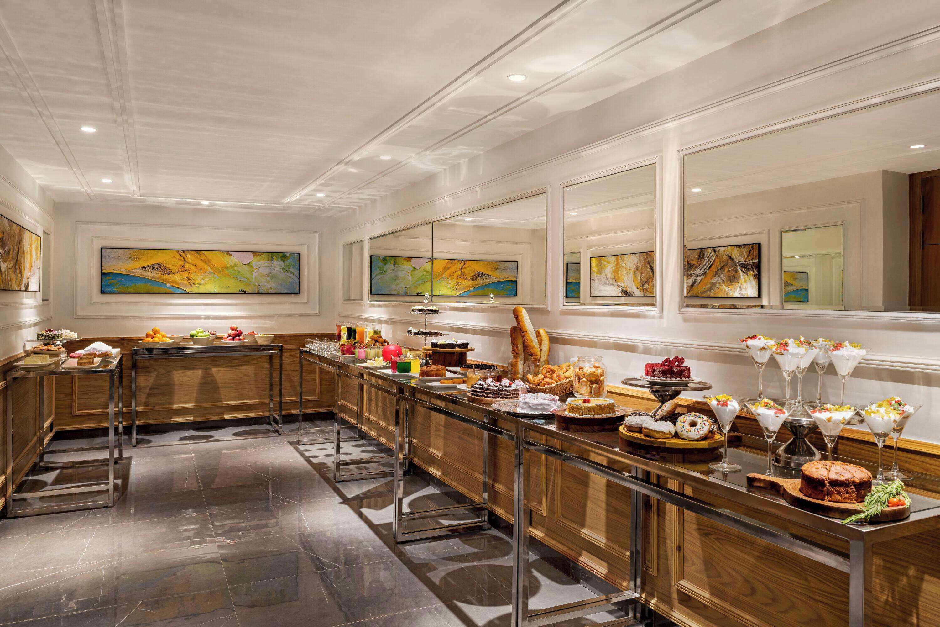 Una larga mesa buffet con diversos alimentos y un cuadro grande en la pared.