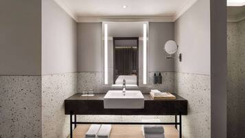 A modern bathroom with a large mirror, a sink, and a towel rack.