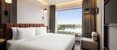 Ein Hotelzimmer mit einem großen Bett, einer Sitzecke und Seeblick.