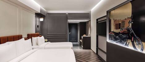 A hotel room with two beds, a large mirror, and a wall-mounted TV.