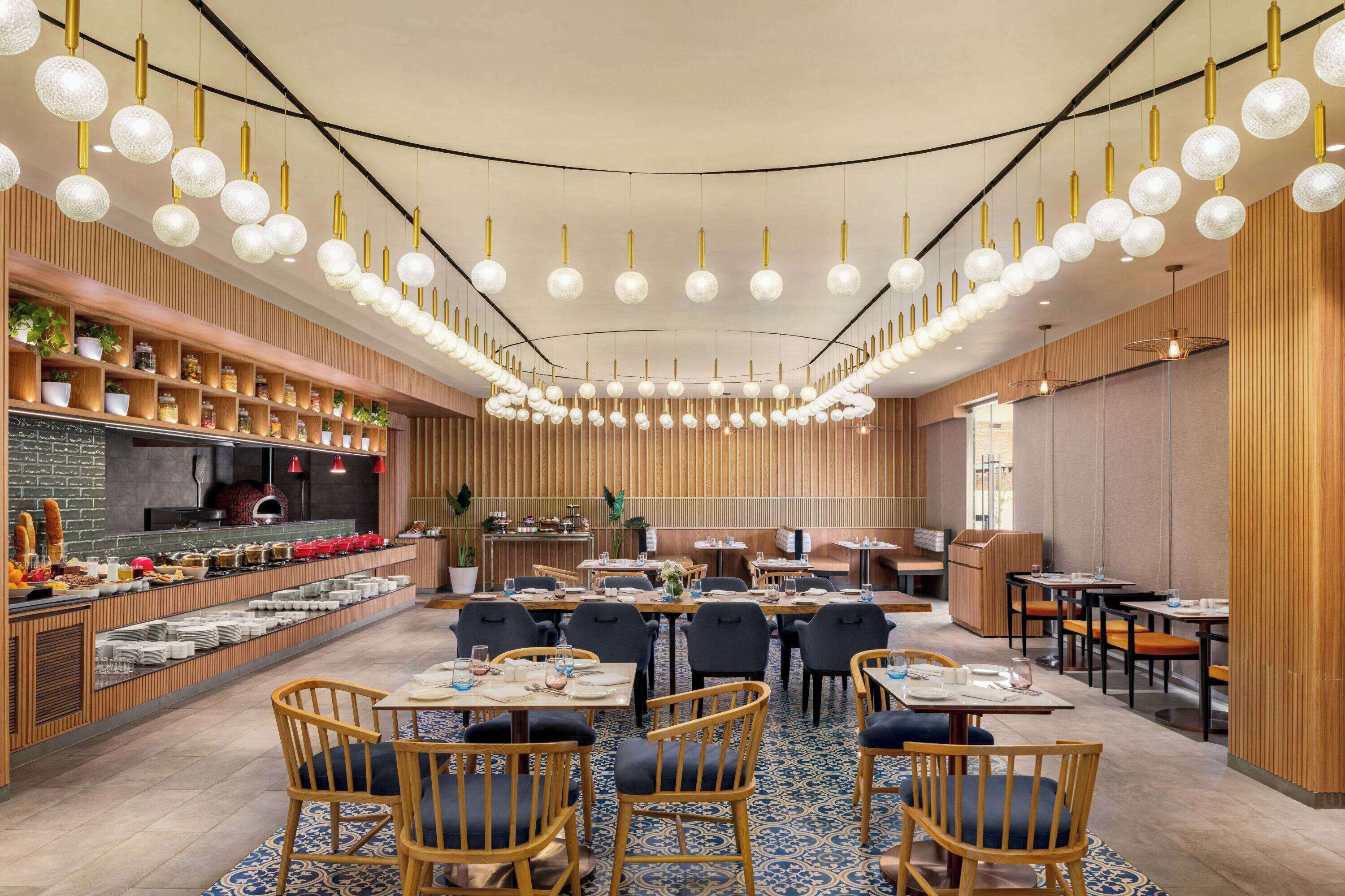 Um restaurante moderno com um bar central, painéis de madeira e diversos tipos de assentos.