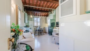A spacious living area with a dining table, sofas, and a kitchen in the background. - Casa Helene in Lucca (Lucca)