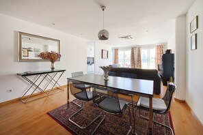 Un espacio de estar moderno con comedor, sofá y cocina al fondo.