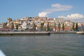 A waterfront cityscape with historic buildings, a prominent tower, and a calm river. - New apartment in the historic center (Lisboa)
