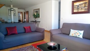 Un salon avec deux canapés, une table basse et un tableau accroché au mur.