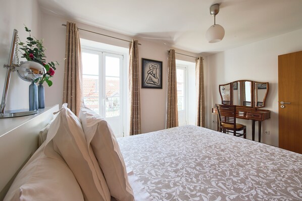 Un dormitorio con cama, cómoda, espejo y ventana con cortinas.