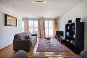 A modern living room with a sofa, a TV, and a bookshelf. - New apartment in the historic center (Lisboa)