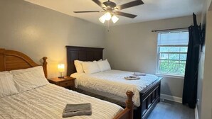 A bedroom with two beds, a ceiling fan, a window with blinds, and a nightstand with a lamp. - 3 Bedrooms Town Home (Charlotte)