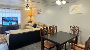 A living room with a sofa, a TV, a ceiling fan, and a dining table with chairs. - 3 Bedrooms Town Home (Charlotte)