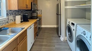 A compact kitchen with wooden cabinets, a microwave, a refrigerator, and a washing machine. - 3 Bedrooms Town Home (Charlotte)