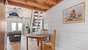 A dining area with a wooden table and chairs, a framed picture on the wall, and a staircase leading to another room.