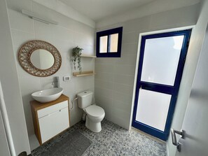 Une salle de bain avec un lavabo blanc, des toilettes et une porte à cadre bleu.