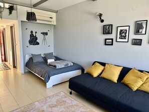 Une chambre moderne avec un lit, un canapé et un climatiseur fixé au mur.