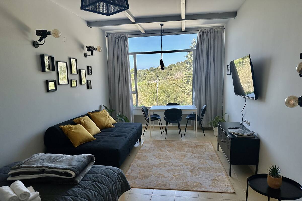 A modern bedroom with a sofa, a desk, and a TV.