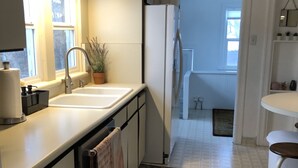 A modern kitchen with a sink, countertop, and a potted plant. There is a refrigerator and a window with curtains. - Spacious Sugarhouse Bungalow close to downtown and the canyons! (Salt Lake City)