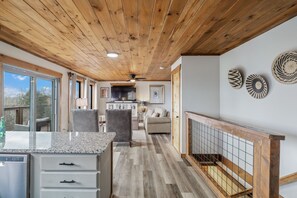 Una cocina amplia con encimera de granito, techo de madera y comedor con sofá y sillas.