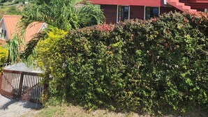 A two-story house with a balcony, surrounded by greenery and hills in the background. - Majestic views  of Pitons, Caribbean sea, amazing sunsets right from your room (Choiseul)