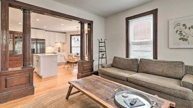 A spacious living room with a wooden coffee table, a gray sofa, and a view of the kitchen through an open doorway. - Family-Friendly Salem Apt: Near Dtwn Sites! (Salem)