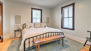 A bedroom with a bed, a bench, two bedside tables, and two windows with blinds. - Family-Friendly Salem Apt: Near Dtwn Sites! (Salem)
