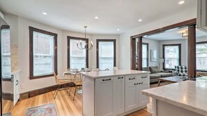 A spacious kitchen with a central island, large windows, and a dining area with a chair and table. - Family-Friendly Salem Apt: Near Dtwn Sites! (Salem)
