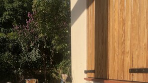 Un espace extérieur ensoleillé, aménagé avec une table en bois et un banc rembourré.