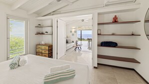 A modern hotel room with a large bed, a ceiling fan, a view of the sea, and a balcony with outdoor seating. - Villa blue Oasis, Coral Estate, Curacao (Willemstad, Curacao, Curacao, Caribbean)