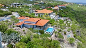 A residential area with houses, a swimming pool, and a hilly landscape. - Villa blue Oasis, Coral Estate, Curacao (Willemstad, Curacao, Curacao, Caribbean)