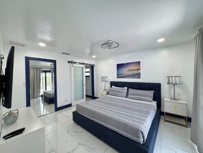 Une chambre moderne avec un grand lit, un téléviseur à écran plat et un tableau représentant une jetée accroché au mur.