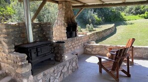 Relax by the stone-built fireplace in a secluded outdoor seating area, sheltered by a pergola.