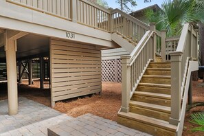 A residential property with a numbered address sign, a wooden staircase, and a covered outdoor area. - Kiawah Exclusives | 1031 Sparrow Cottage (Johns Island)