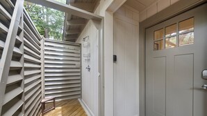 Eine Holzterrasse mit einer weißen Tür und einem Fenster mit vielen Sprossen.