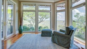 A spacious room with large windows, a ceiling fan, and two upholstered chairs. - Kiawah Exclusives | 65 Persimmon Court (Johns Island)