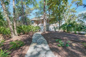 Stroll through the serene gardens to a traditional house surrounded by lush greenery.