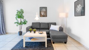A modern living room with a grey sofa, a white coffee table, a potted plant, and a framed picture on the wall. - Casa Torremuelle I – 2-Bedroom Vacation Home with Pool, BBQ & Patio (Benalmádena)