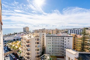 A high-rise building with multiple balconies, a parking area, and a view of the sea. - La Nogalera Skyline | Stylish Apartment with Panoramic Sea Views & Pools in Torremolinos (Torremolinos)