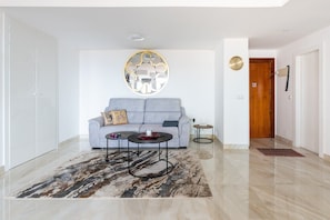 Un salon moderne avec un canapé gris, deux tables basses, un tapis à motifs et un élément décoratif mural.