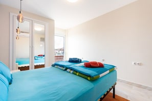 Une chambre d’hôtel avec un lit, une salle de bain avec un miroir et une vue sur la piscine depuis la porte.