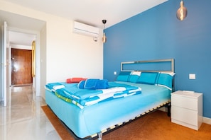 Une chambre à coucher comprenant un lit, une table de chevet et un appareil de climatisation.