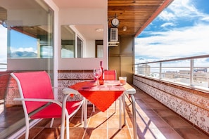Un balcon avec une table et des chaises, une horloge et une vue sur la ville.