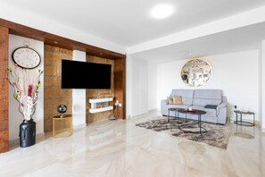 A modern living room with a flat-screen TV, a grey sofa, a coffee table, and a decorative wall clock. - La Nogalera Skyline | Stylish Apartment with Panoramic Sea Views & Pools in Torremolinos (Torremolinos)