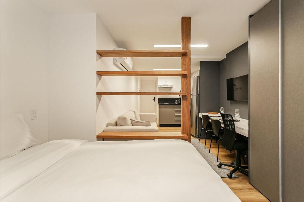 Ein modernes Hotelzimmer mit einem Bett, einer Couch, einem Schreibtisch mit Stühlen und einem Fernseher.