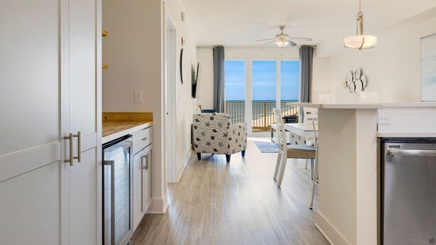 Eine moderne Küche mit weißen Schränken, einer Holz Arbeitsplatte und einem Essbereich mit Blick auf den Strand.