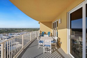 Un balcon avec une table et des chaises, une vue sur la ville et un ciel dégagé.