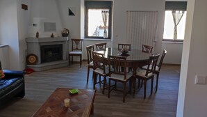 A living room with a fireplace, a dining table with chairs, and a sofa. - Casa Cruz. (Trinta)