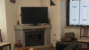 A living room with a fireplace, a flat-screen TV, a sofa, and a coffee table. - Casa Cruz. (Trinta)