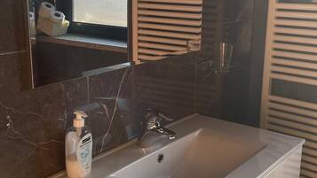 A modern bathroom with a large mirror, a white vanity, and a built-in sink.