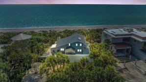 A beachfront property with a large house, a smaller building, and a gazebo.